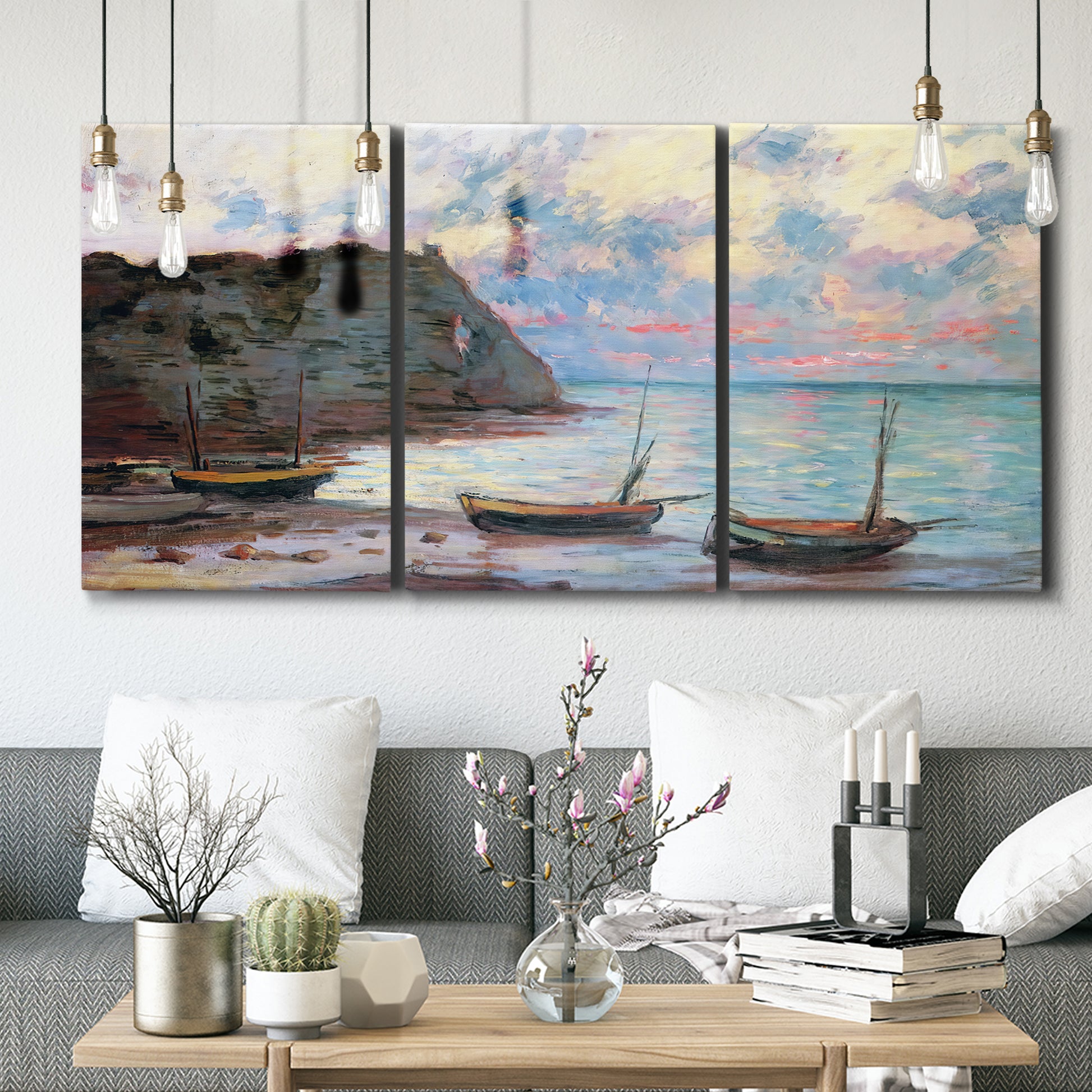 Three-panel canvas wall art featuring golden coastal sunset with cliffs, displayed in a modern living room above seating.