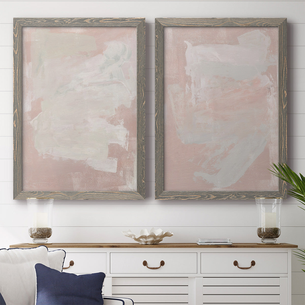 Set of two gray barnwood framed canvas prints depicting a coordinated art pair of soft blush and white painterly fields rendered as minimalist color-field abstracts above a dining room sideboard.