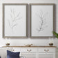 Set of two gray barnwood framed canvas prints depicting a coordinated art pair of single continuous-line leafy branches rendered as minimalist botanical line drawings above a dining room sideboard.
