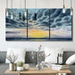 Three-panel canvas wall art featuring tropical coastal sunset over water, displayed in a modern living room above seating.
