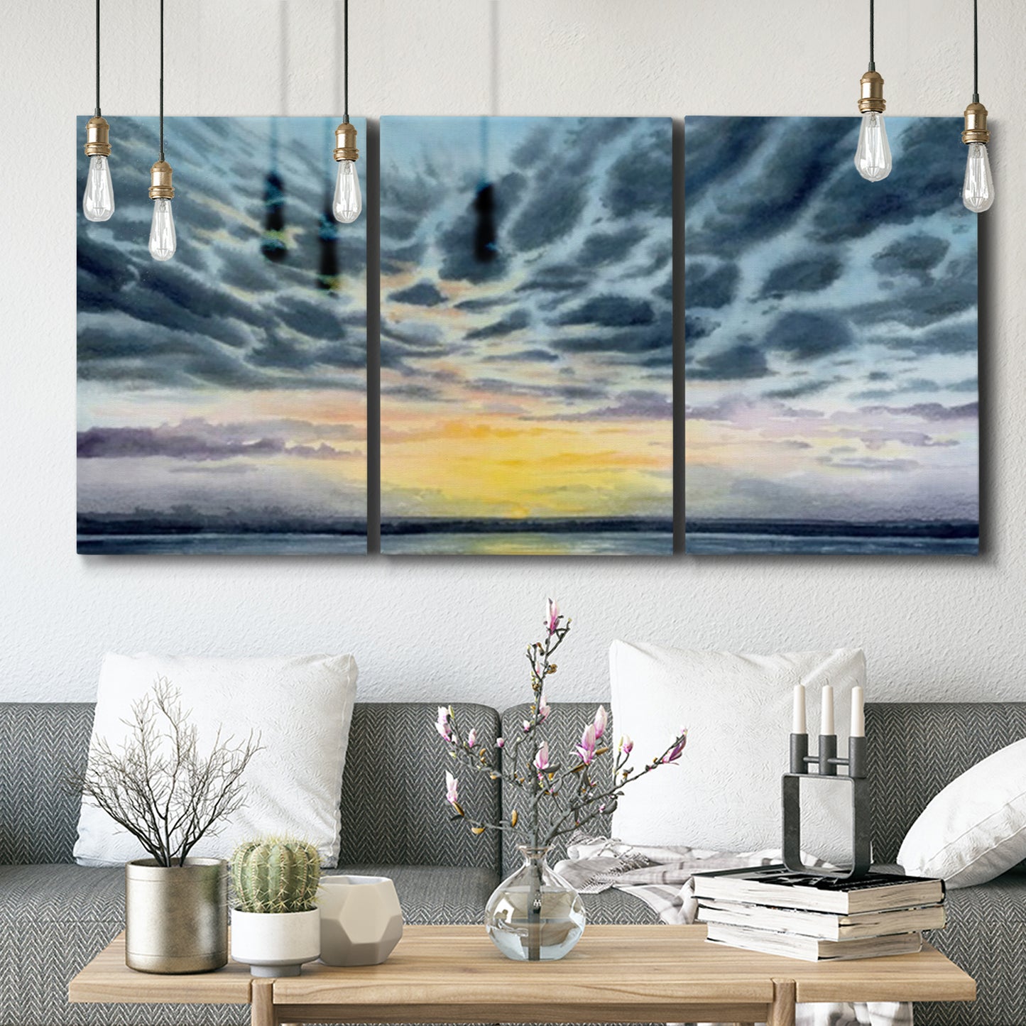 Three-panel canvas wall art featuring tropical coastal sunset over water, displayed in a modern living room above seating.