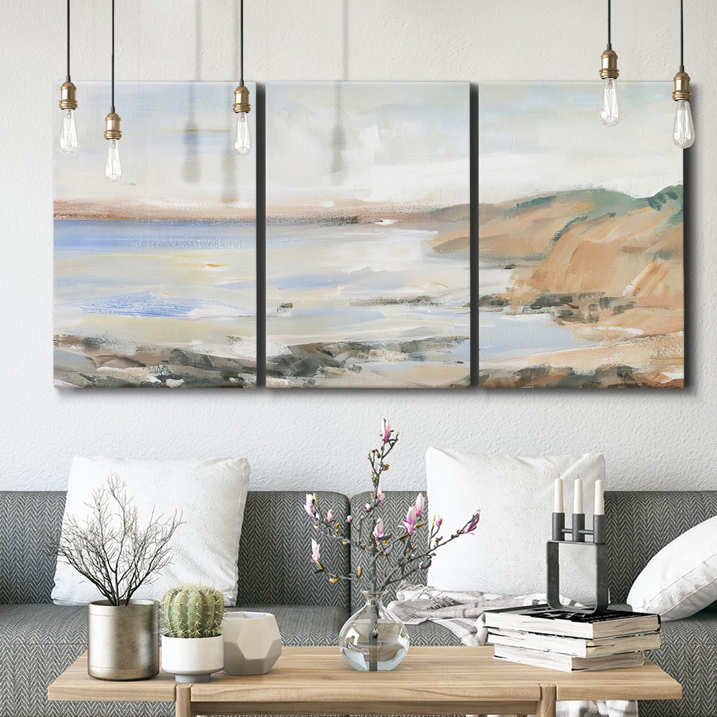 Three-panel canvas wall art featuring coastal shoreline landscape study, displayed in a modern living room above seating.