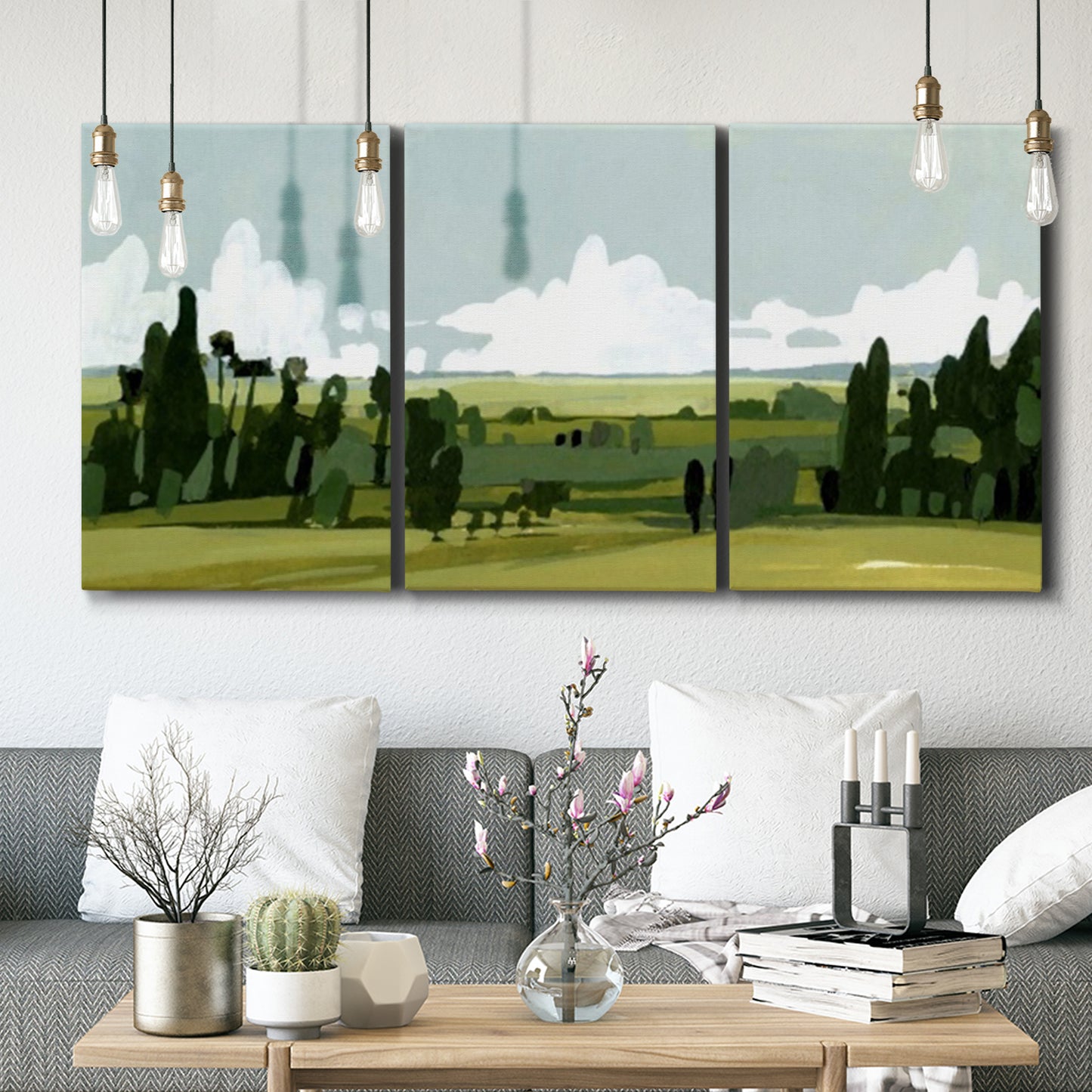 Three-panel canvas wall art featuring lush green summer countryside, displayed in a modern living room above seating.