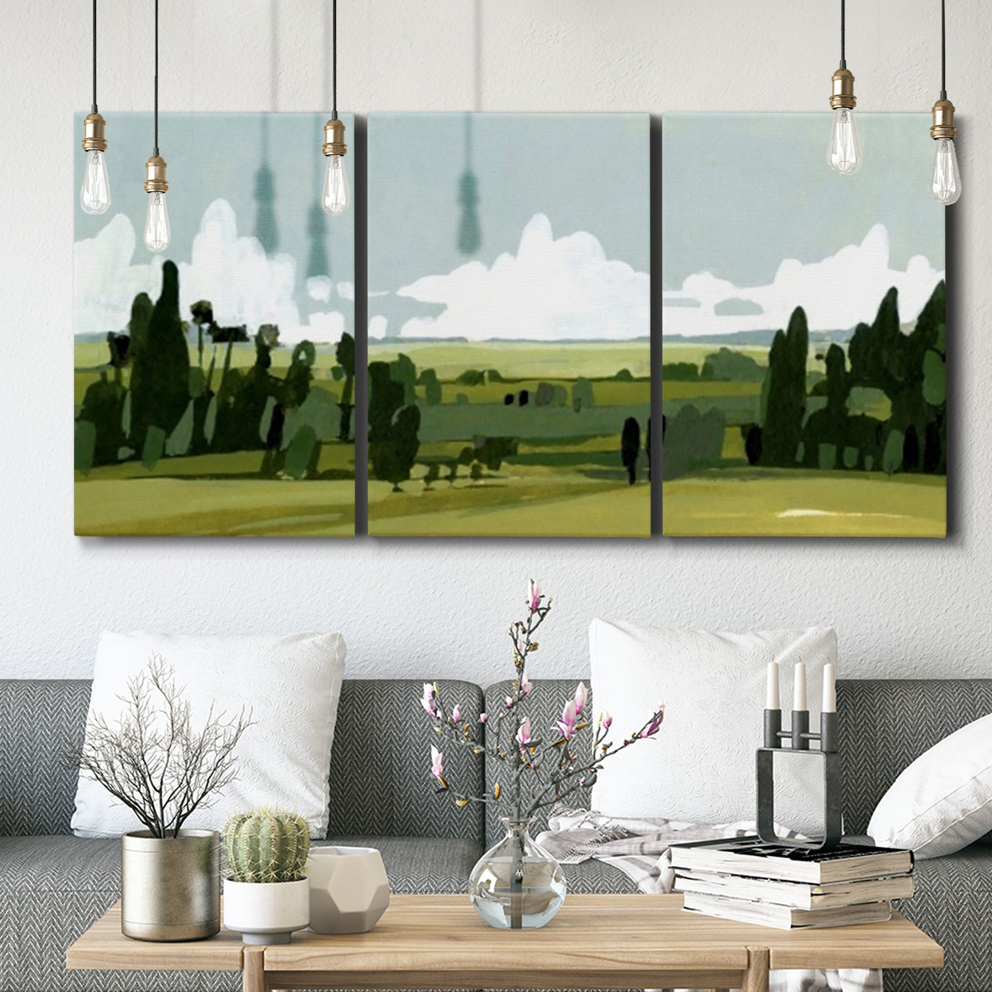 Three-panel canvas wall art featuring lush green summer countryside, displayed in a modern living room above seating.