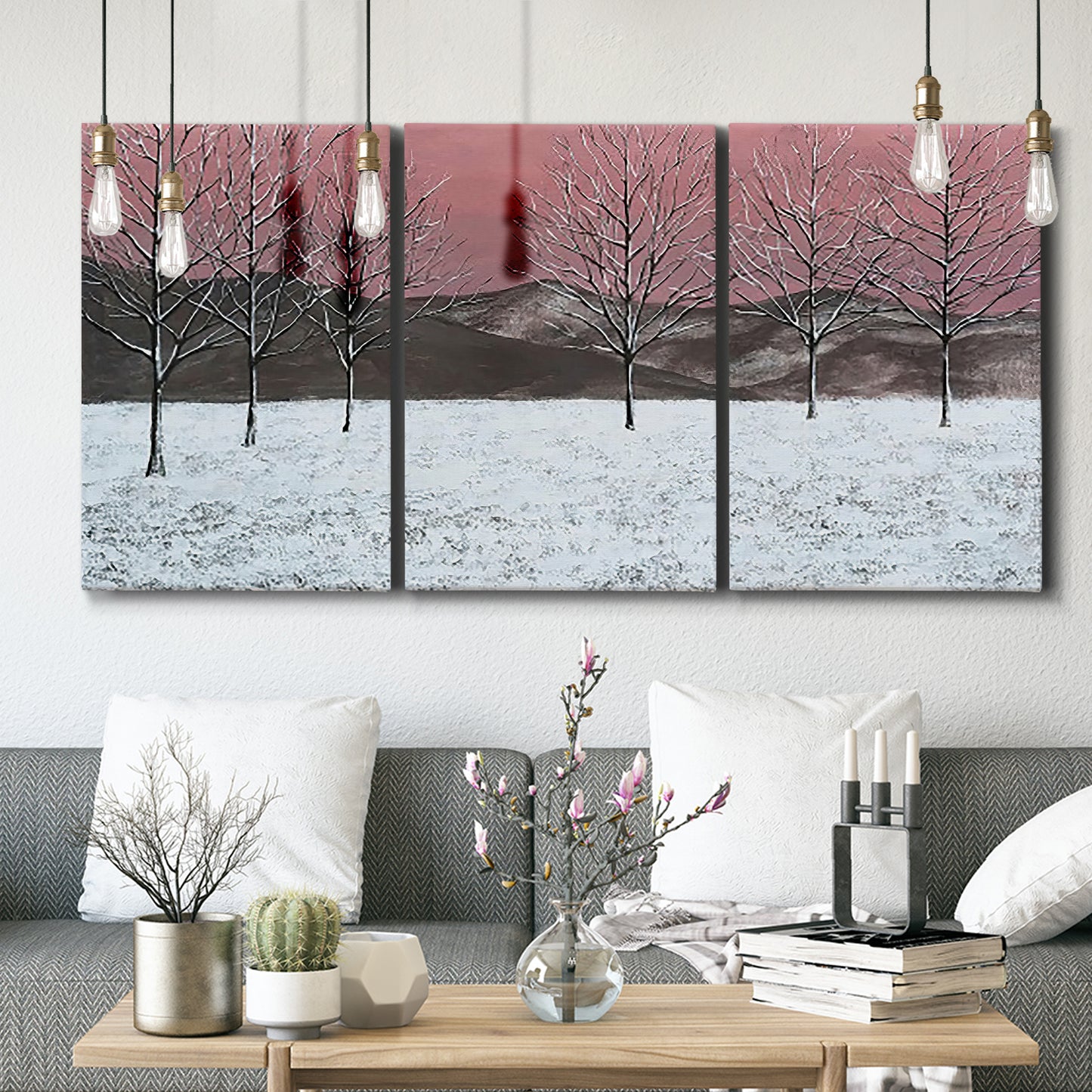 Three-panel canvas wall art featuring winter sunset snowfall landscape, displayed in a modern living room above seating.