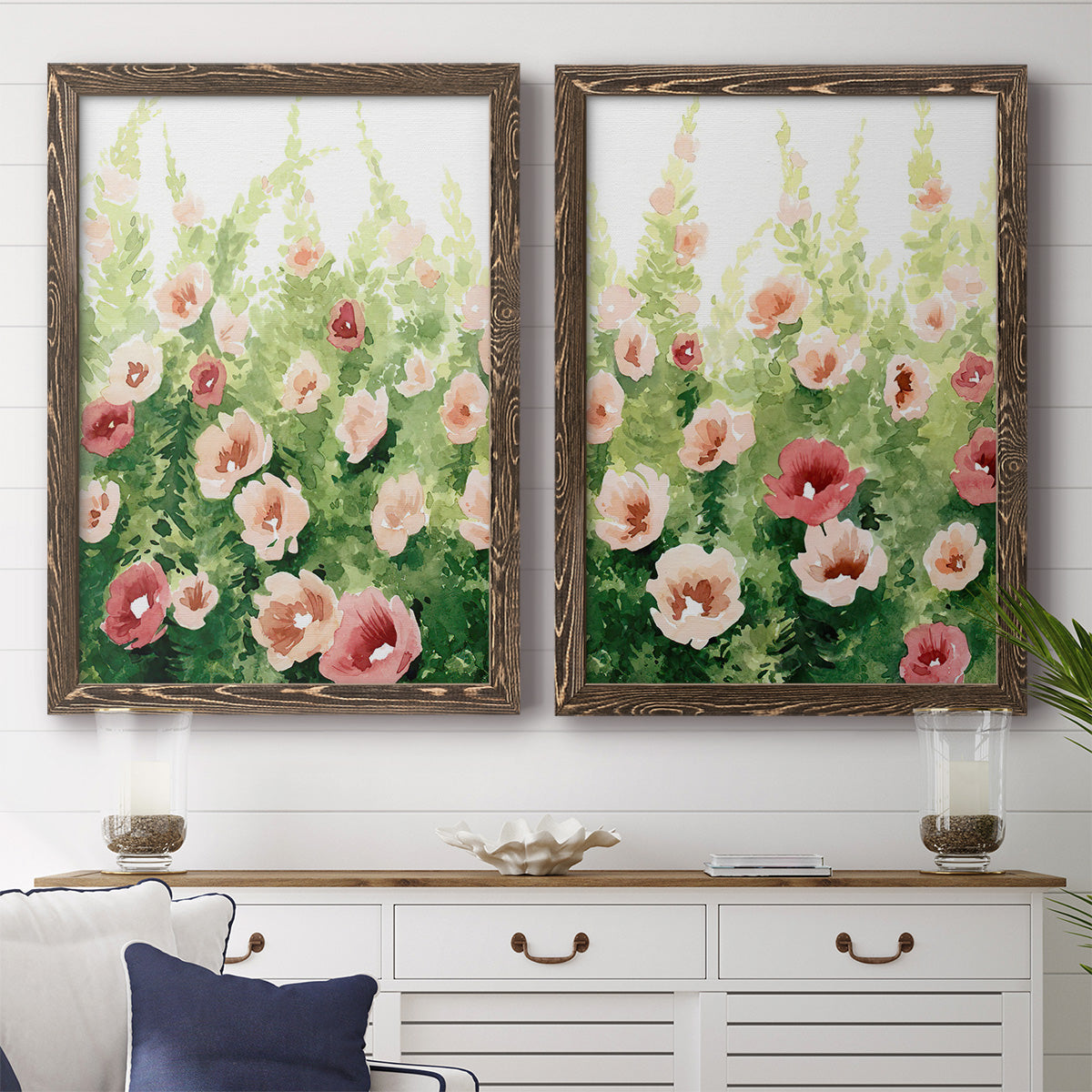Set of two walnut barnwood framed canvas prints depicting a coordinated art pair of a field of pink coral and white flowers rendered as luminous impressionistic floral paintings above a dining room sideboard.