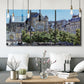 Three-panel canvas wall art featuring gothic church within city setting, displayed in a modern living room above seating.