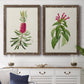 Set of two walnut barnwood framed canvas prints depicting a coordinated art pair of pink flowering plant specimens rendered as vintage botanical plate illustrations above a dining room sideboard.