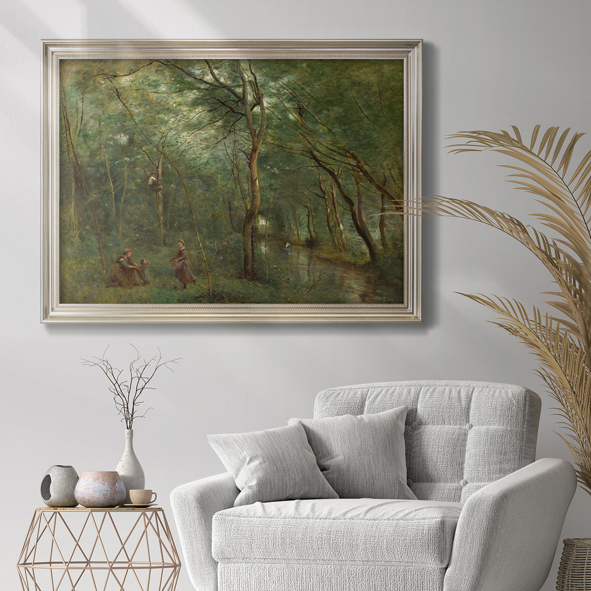 Traditional rural landscape scene with figures by Jean-Baptiste-Camille Corot in an ornate champagne frame displayed in a bright interior setting.