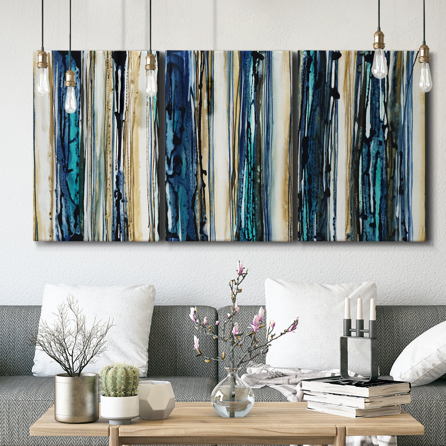 Three-panel canvas wall art featuring vertical blue abstract streaks, displayed in a modern living room above seating.