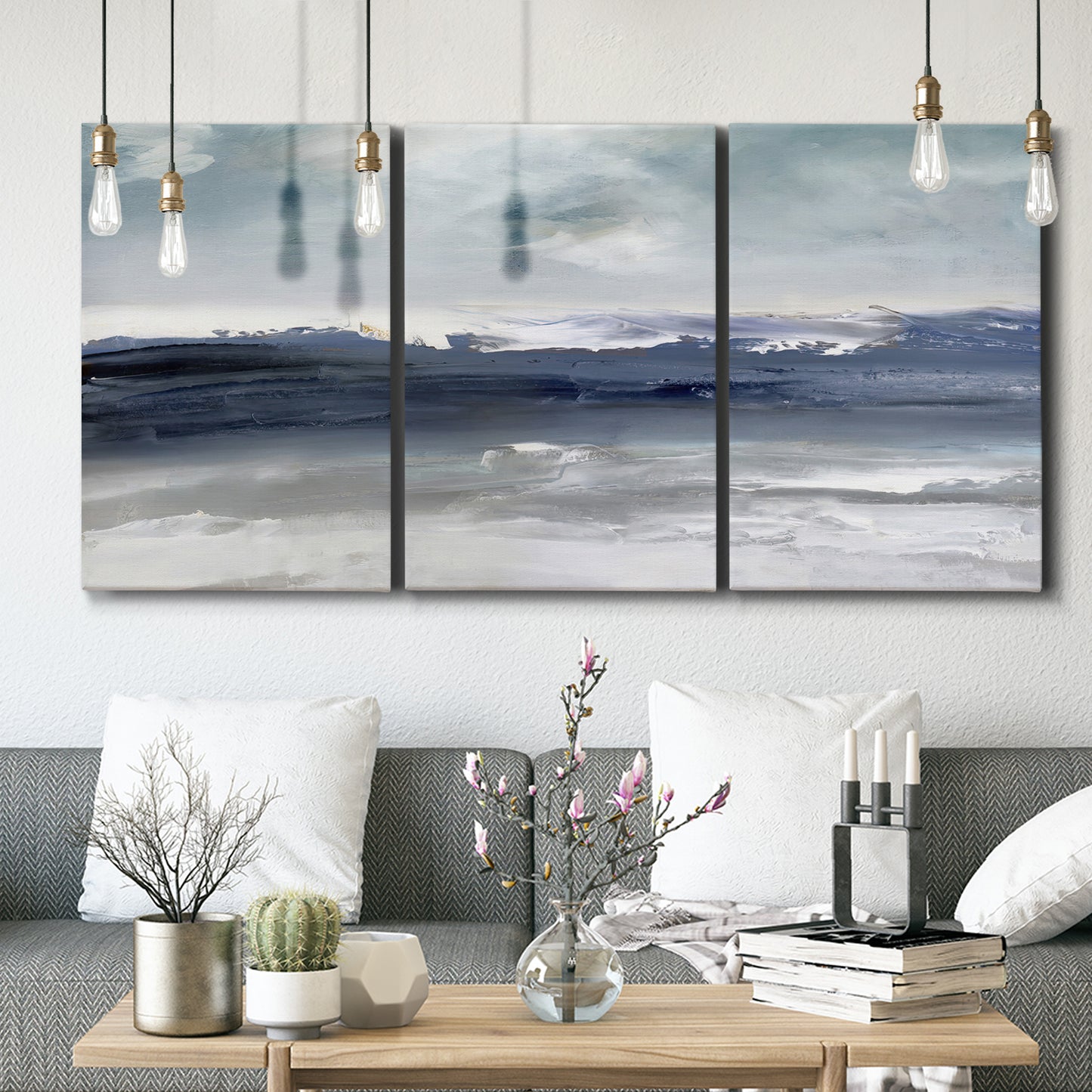 Three-panel canvas wall art featuring abstract coastal tones and movement, displayed in a modern living room above seating.