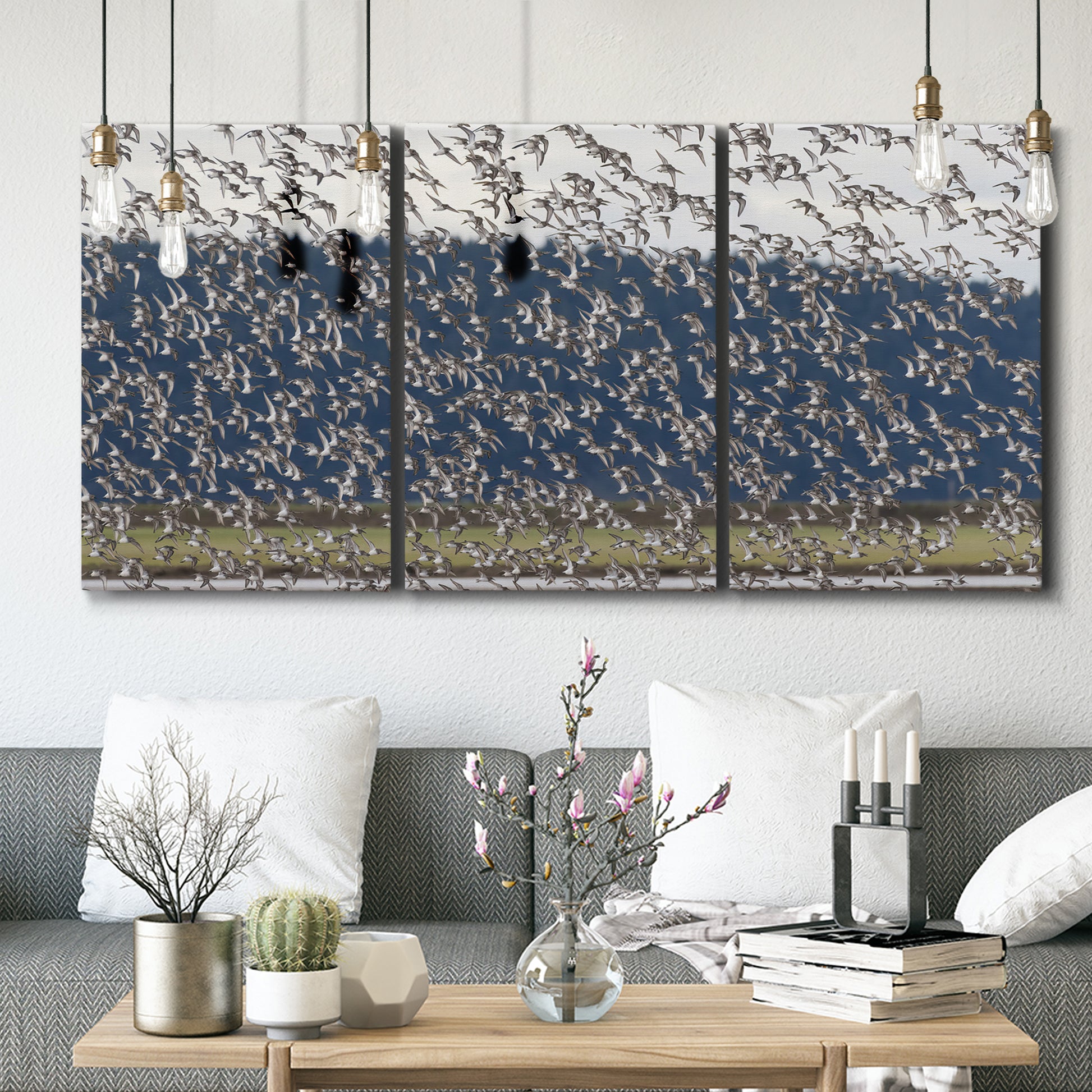 Three-panel canvas wall art featuring group of animals in open field, displayed in a modern living room above seating.