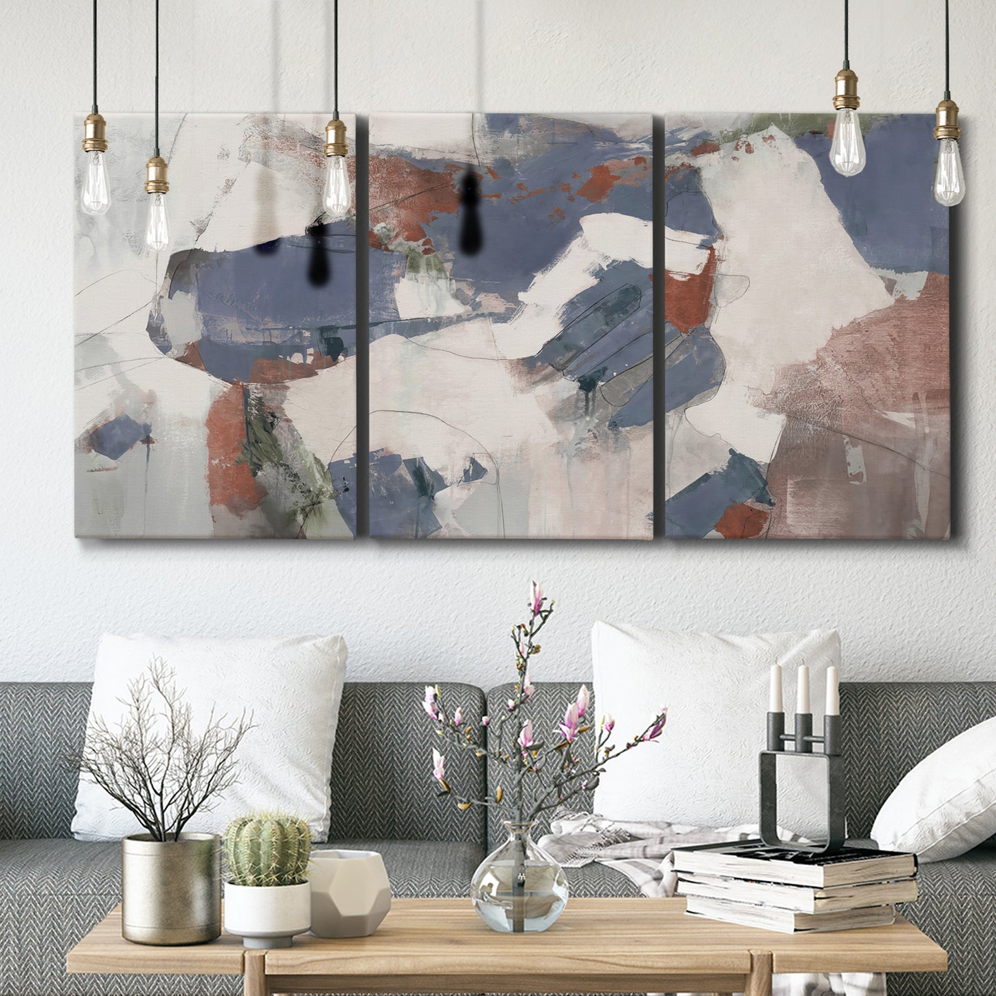Three-panel canvas wall art featuring cool blue abstract layered composition, displayed in a modern living room above seating.