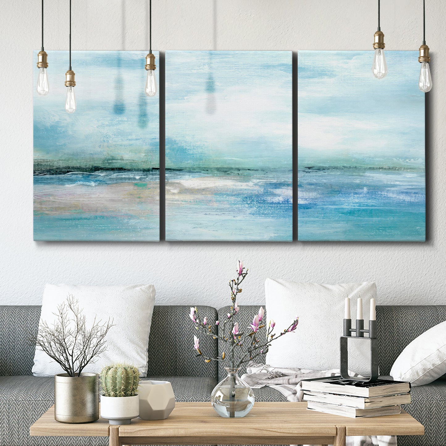 Three-panel canvas wall art featuring sunset silhouette over coastal water, displayed in a modern living room above seating.