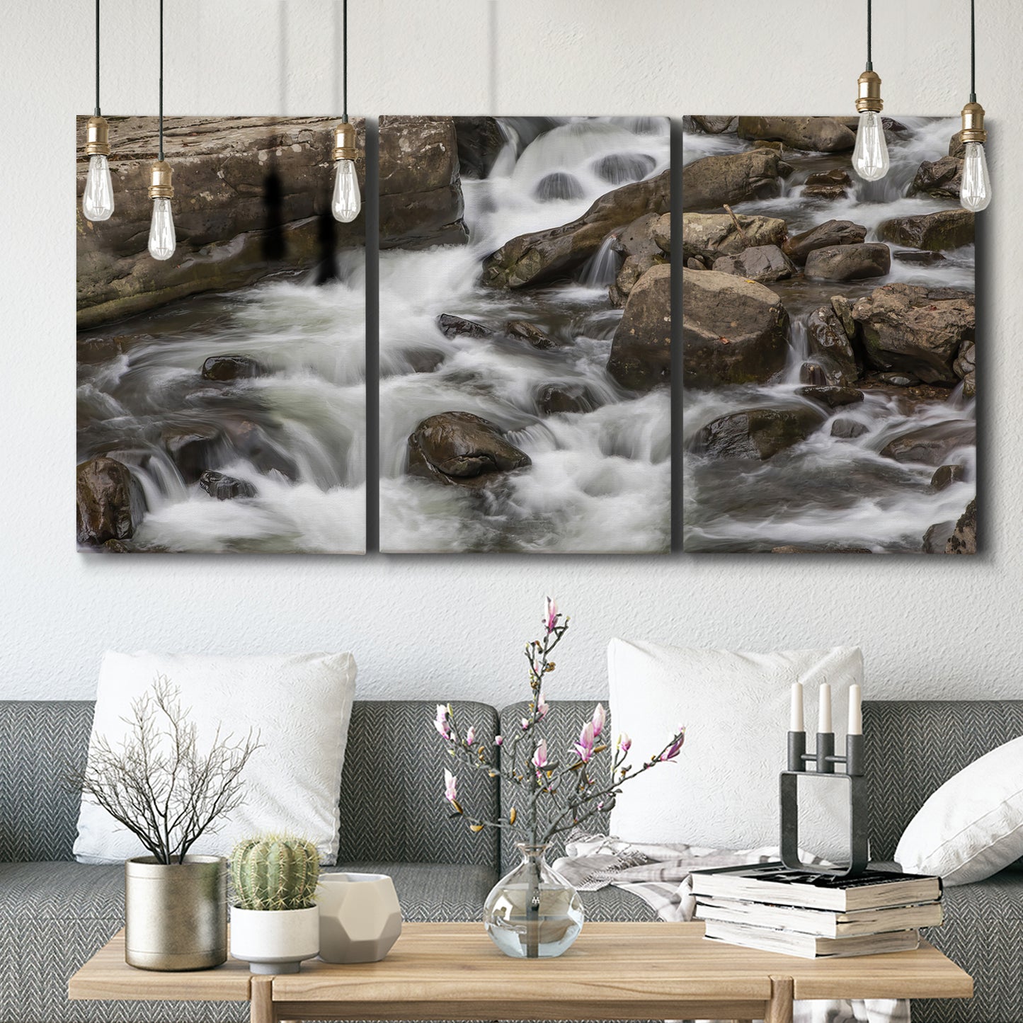 Three-panel canvas wall art featuring rushing river water over rocks, displayed in a modern living room above seating.