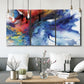 Three-panel canvas wall art featuring vibrant abstract color explosion, displayed in a modern living room above seating.
