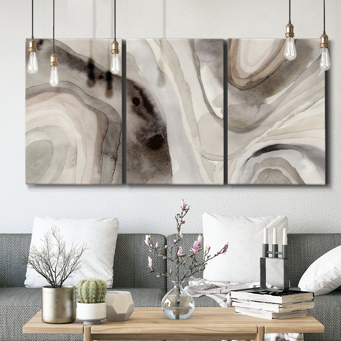 Three-panel canvas wall art featuring layered stone inspired abstract forms, displayed in a modern living room above seating.