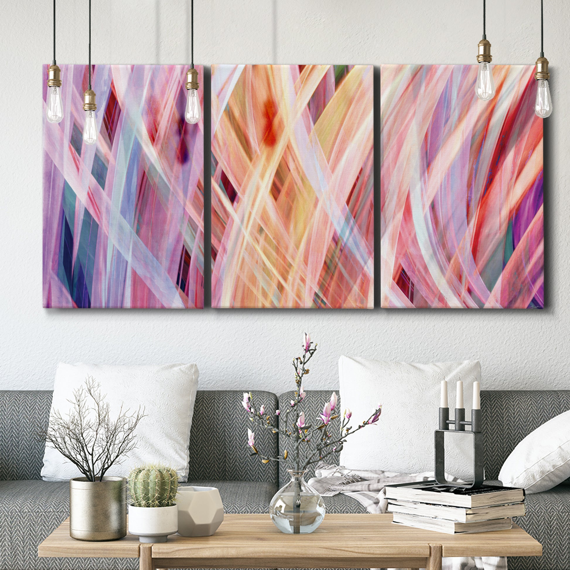 Three-panel canvas wall art featuring layered modern abstract color ribbons, displayed in a modern living room above seating.