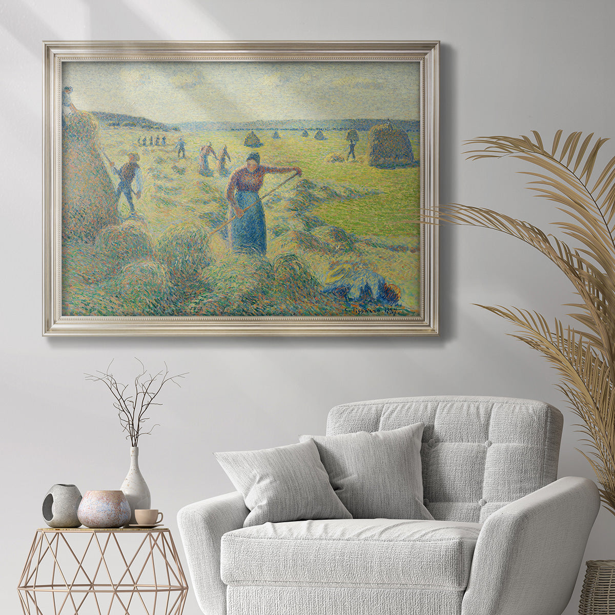 Impressionist rural hay harvest landscape by Camille Pissarro in an ornate champagne frame displayed in a bright interior setting.