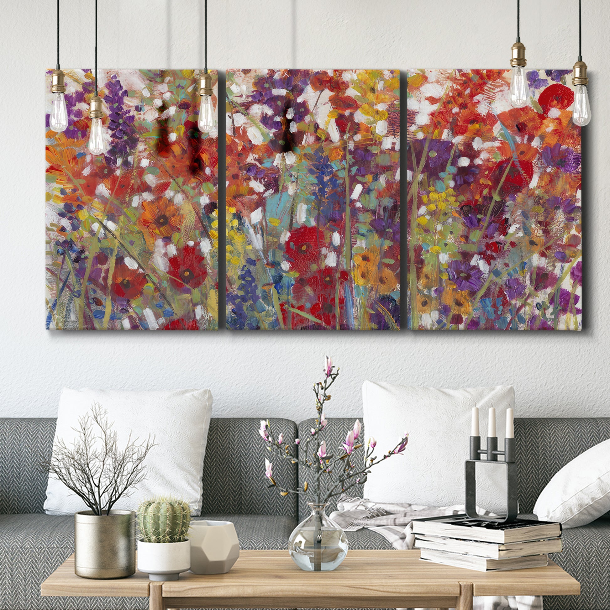 Three-panel canvas wall art featuring colorful floral arrangement, displayed in a modern living room above seating.