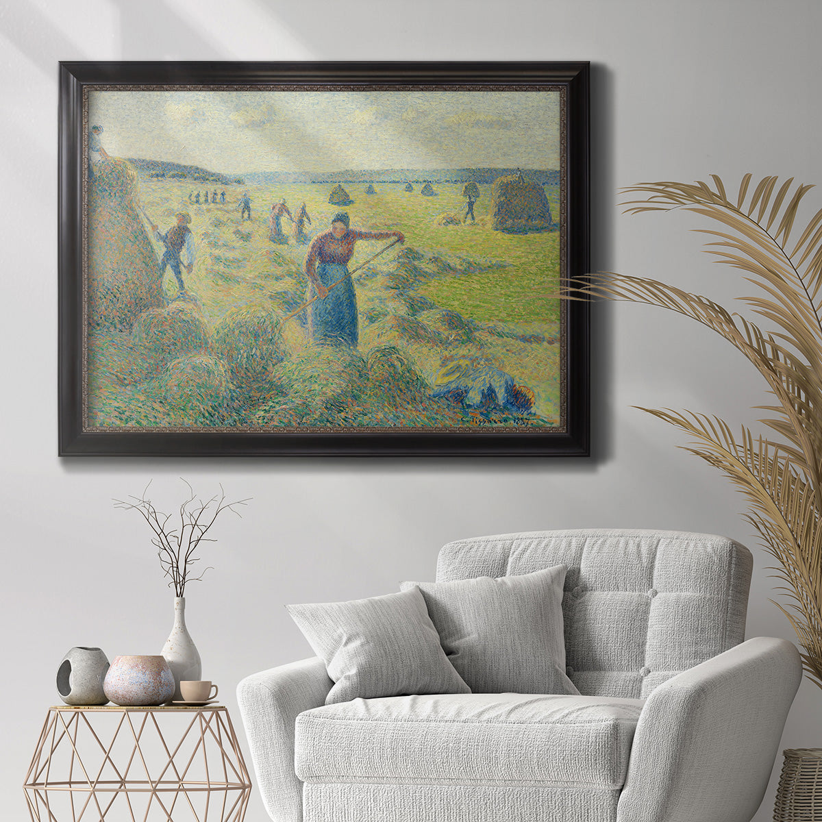 Impressionist rural hay harvest landscape by Camille Pissarro in an ornate black frame with gilded inner detail displayed in a bright interior setting.