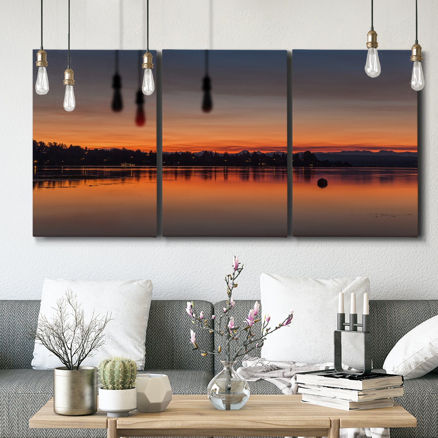 Three-panel canvas wall art featuring glowing sunset over water, displayed in a modern living room above seating.