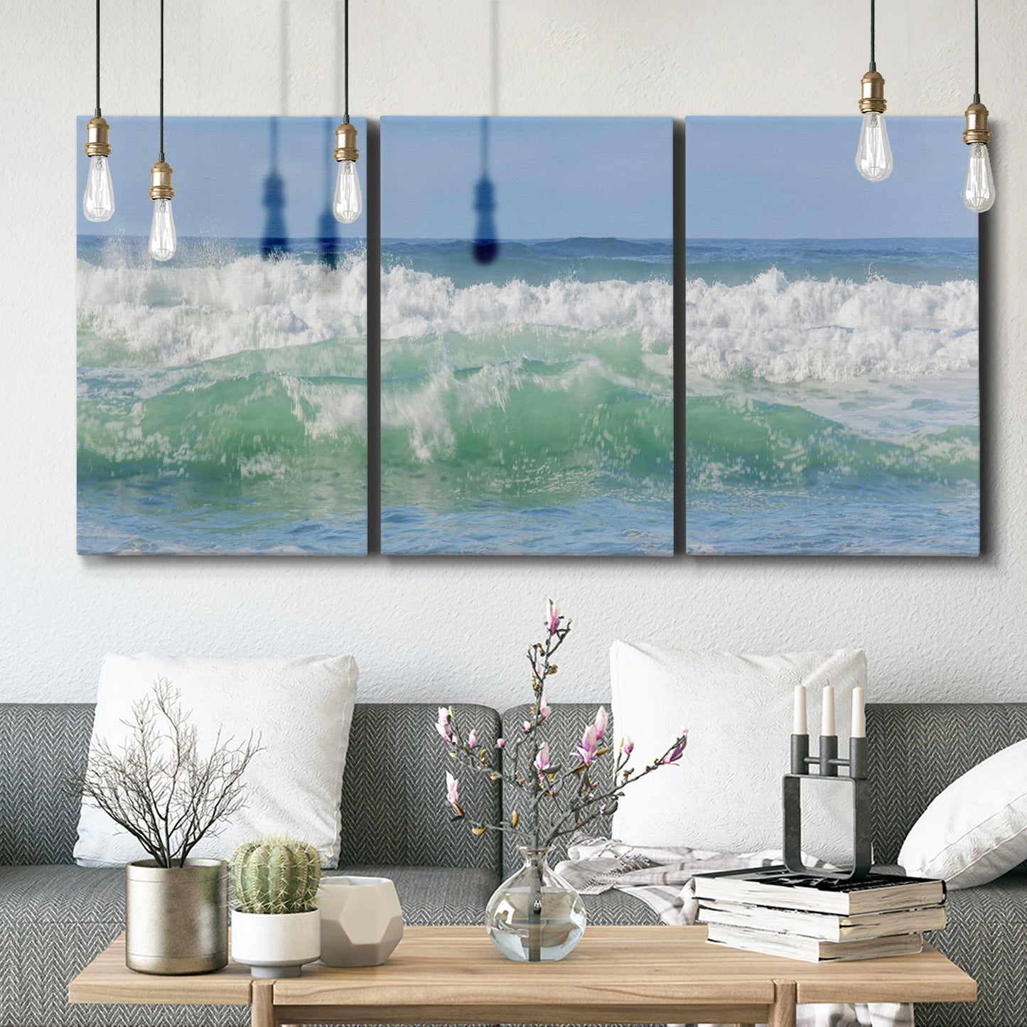 Three-panel canvas wall art featuring coastal waves breaking ashore, displayed in a modern living room above seating.