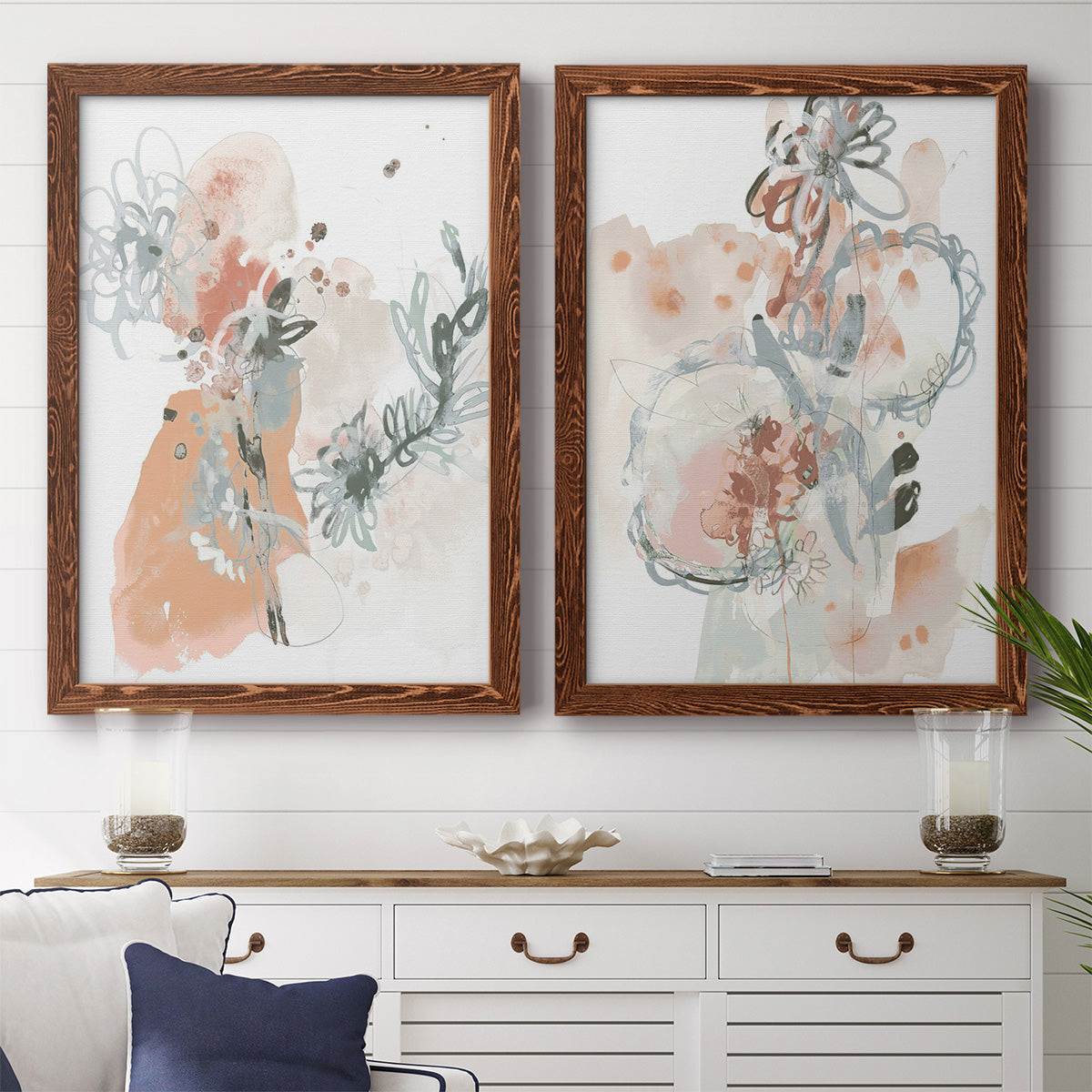 Set of two maple barnwood framed canvas prints depicting a coordinated art pair of loose blush gray and coral floral gestures rendered as abstract watercolor botanicals above a dining room sideboard.