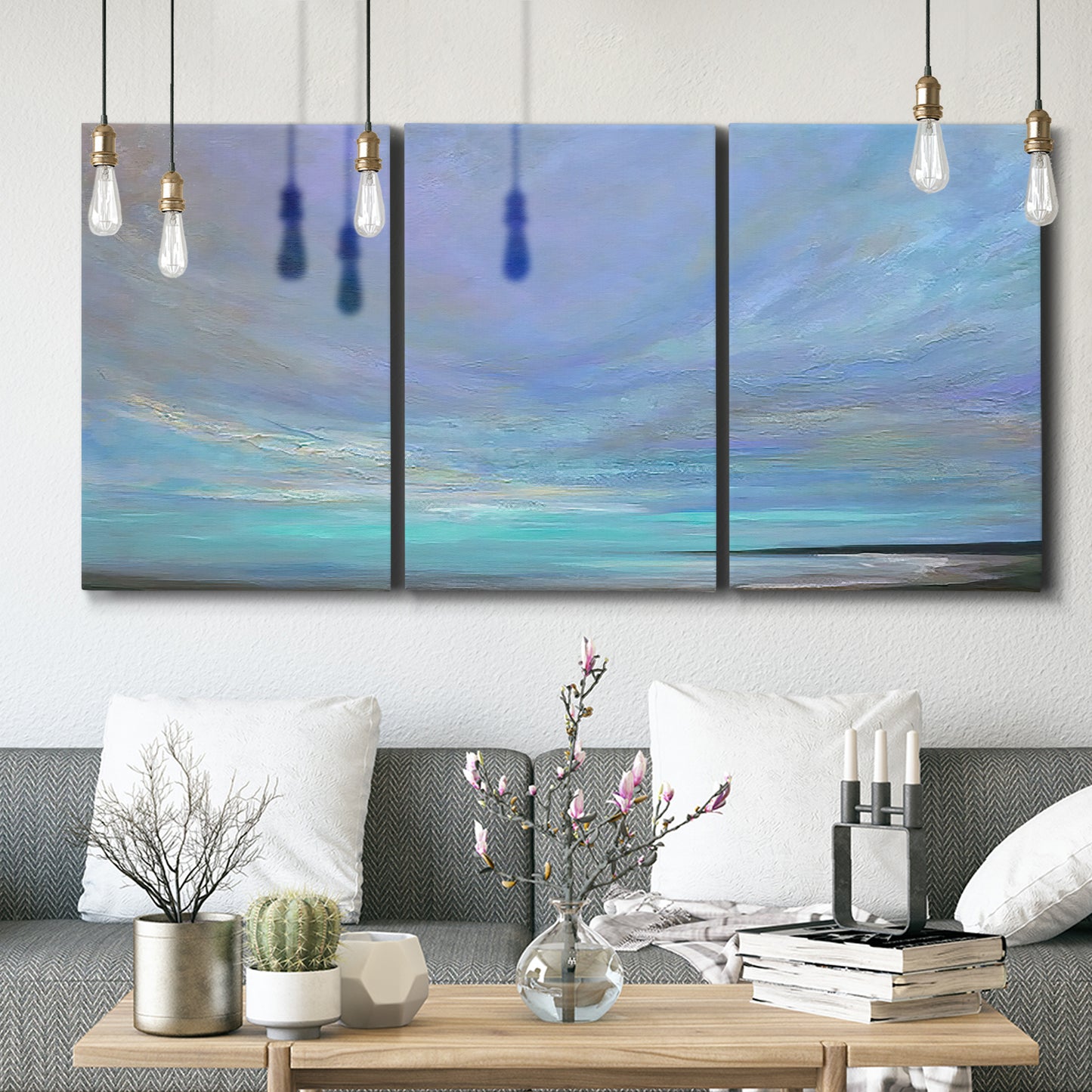 Three-panel canvas wall art featuring coastal shoreline with gentle surf, displayed in a modern living room above seating.