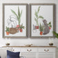 Set of two gray barnwood framed canvas prints depicting a coordinated art pair of cats tucked among collections of potted houseplants rendered as whimsical botanical animal illustrations above a dining room sideboard.