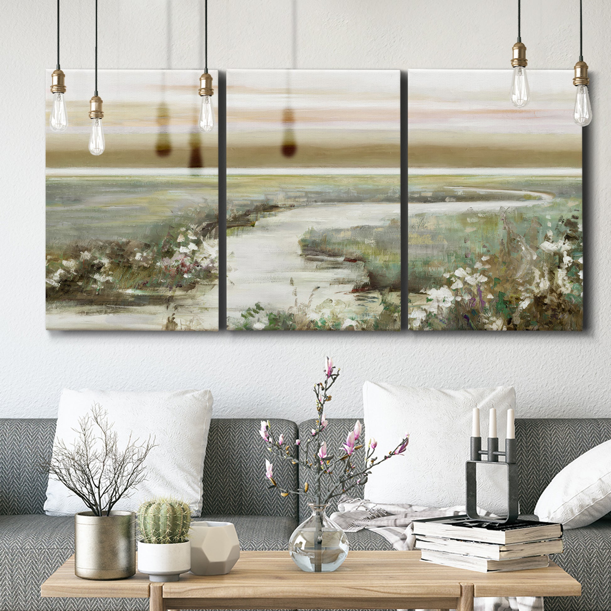 Three-panel canvas wall art featuring pastoral fields under soft sunrise, displayed in a modern living room above seating.