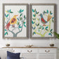 Set of two gray barnwood framed canvas prints depicting a coordinated art pair of stylized colorful birds perched among leafy branches rendered as modern folk-art bird illustrations above a dining room sideboard.