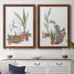 Set of two maple barnwood framed canvas prints depicting a coordinated art pair of cats tucked among collections of potted houseplants rendered as whimsical botanical animal illustrations above a dining room sideboard.