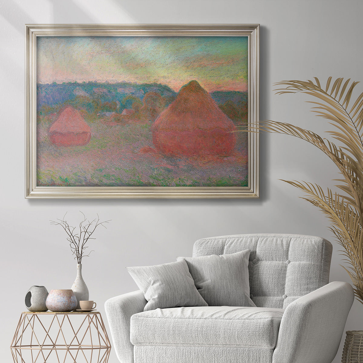 Impressionist haystack series landscape by Claude Monet in an ornate champagne frame displayed in a bright interior setting.