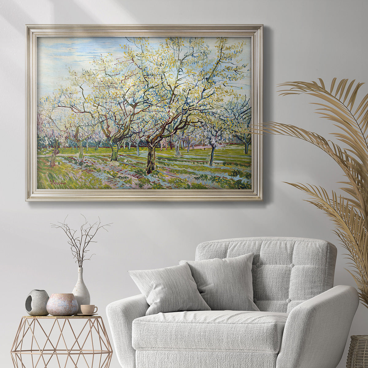 Impressionist white-blossomed orchard landscape by Vincent van Gogh in an ornate champagne frame displayed in a bright interior setting.
