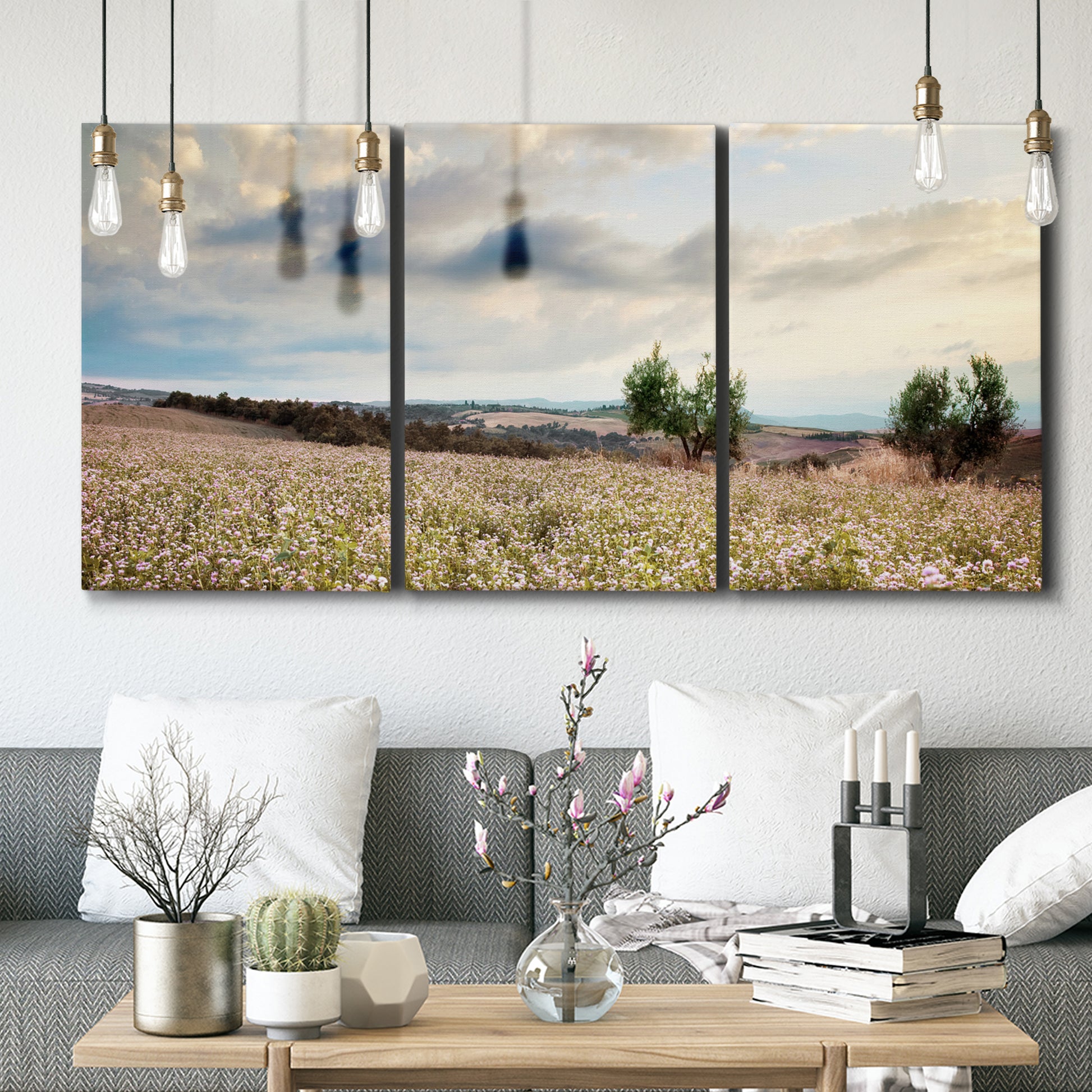 Three-panel canvas wall art featuring wildflowers across tuscan landscape, displayed in a modern living room above seating.