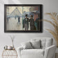 Impressionist urban street scene in the rain by Gustave Caillebotte in an ornate black frame with gilded inner detail displayed in a bright interior setting.