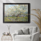 Impressionist white-blossomed orchard landscape by Vincent van Gogh in an ornate black frame with gilded inner detail displayed in a bright interior setting.