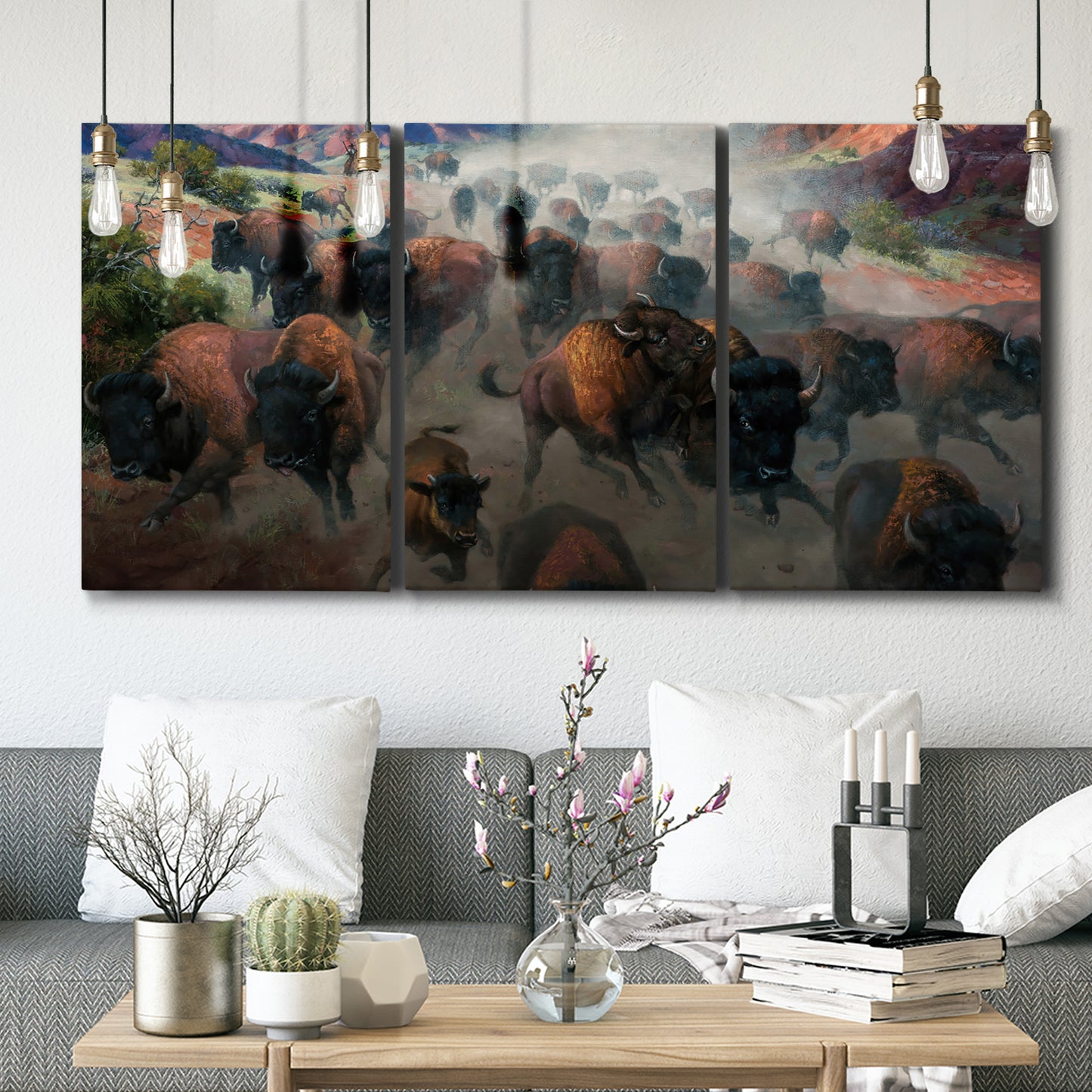Three-panel canvas wall art featuring stormy canyon landscape with animals, displayed in a modern living room above seating.