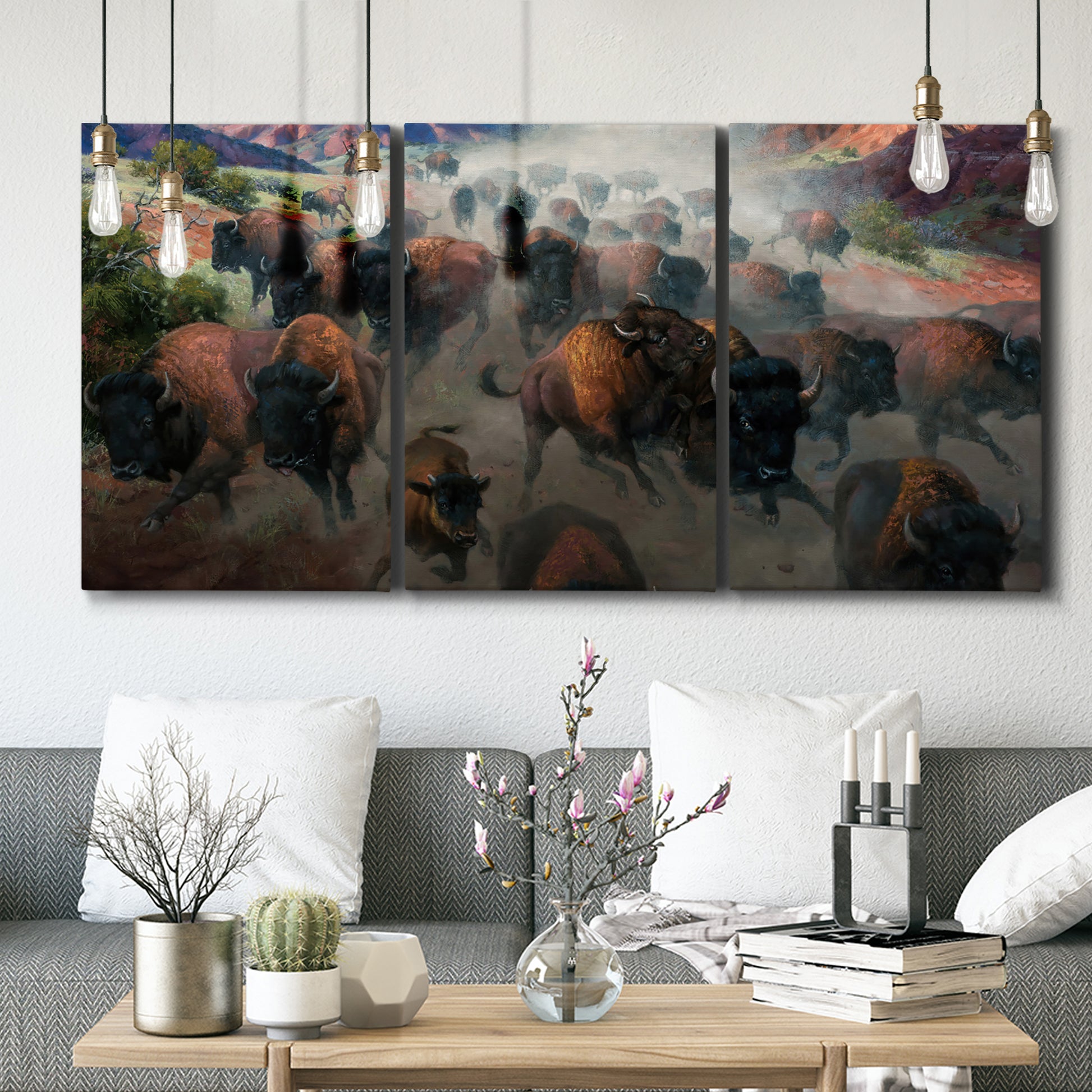 Three-panel canvas wall art featuring stormy canyon landscape with animals, displayed in a modern living room above seating.