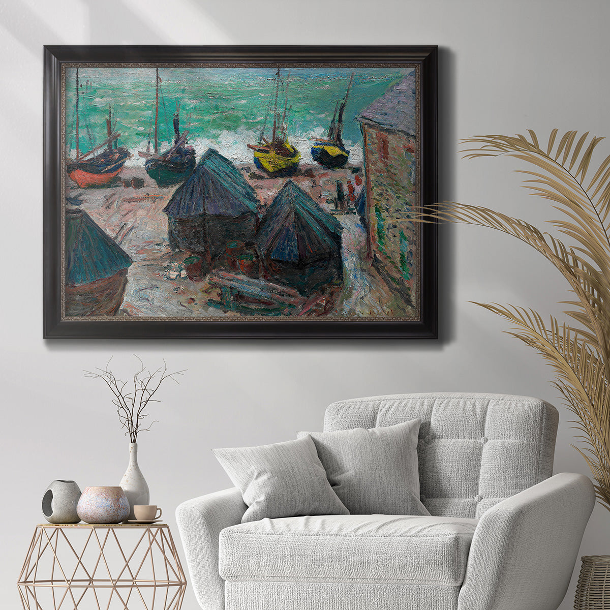 Impressionist coastal beach scene with boats by Claude Monet in an ornate black frame with gilded inner detail displayed in a bright interior setting.