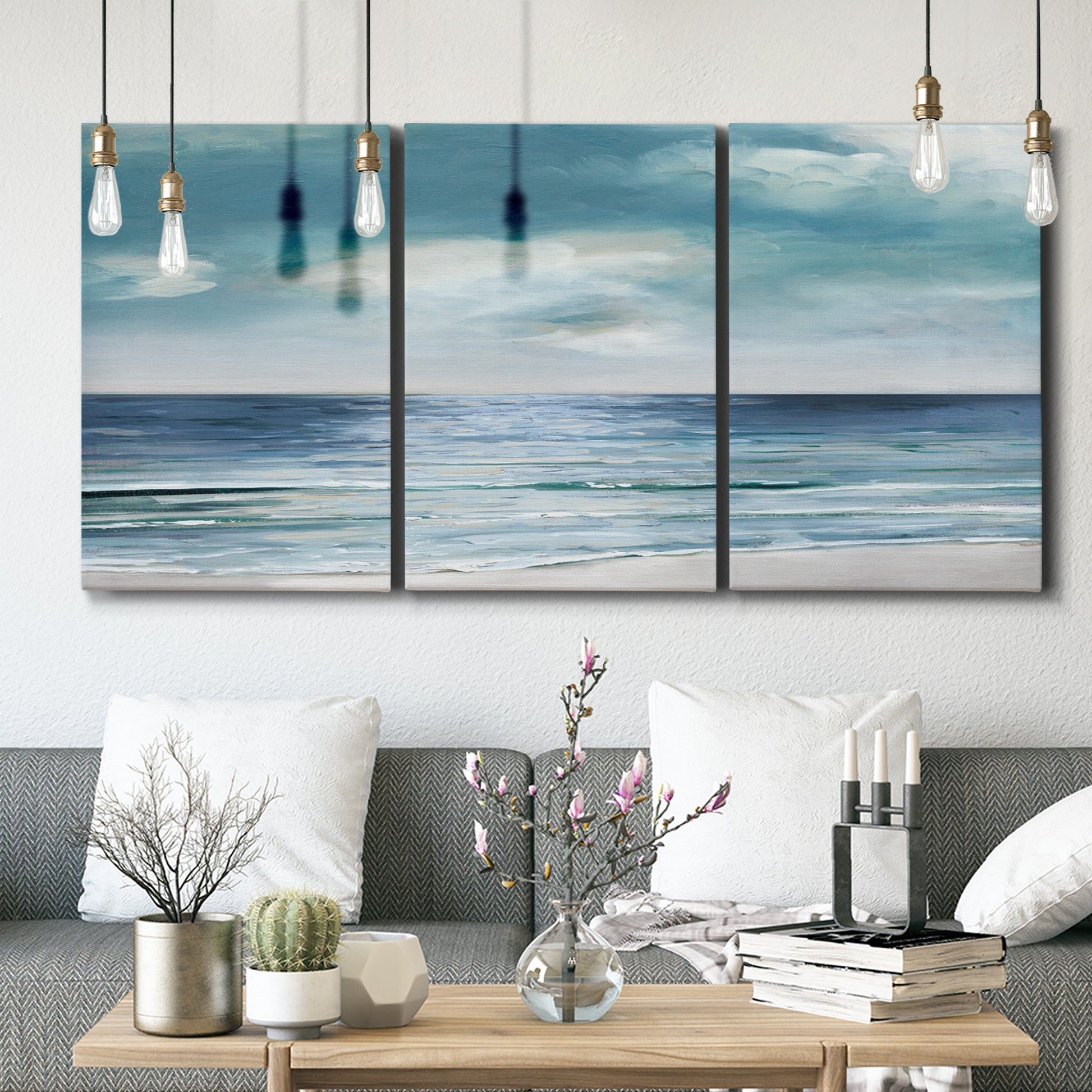 Three-panel canvas wall art featuring calm coastal shoreline, displayed in a modern living room above seating.