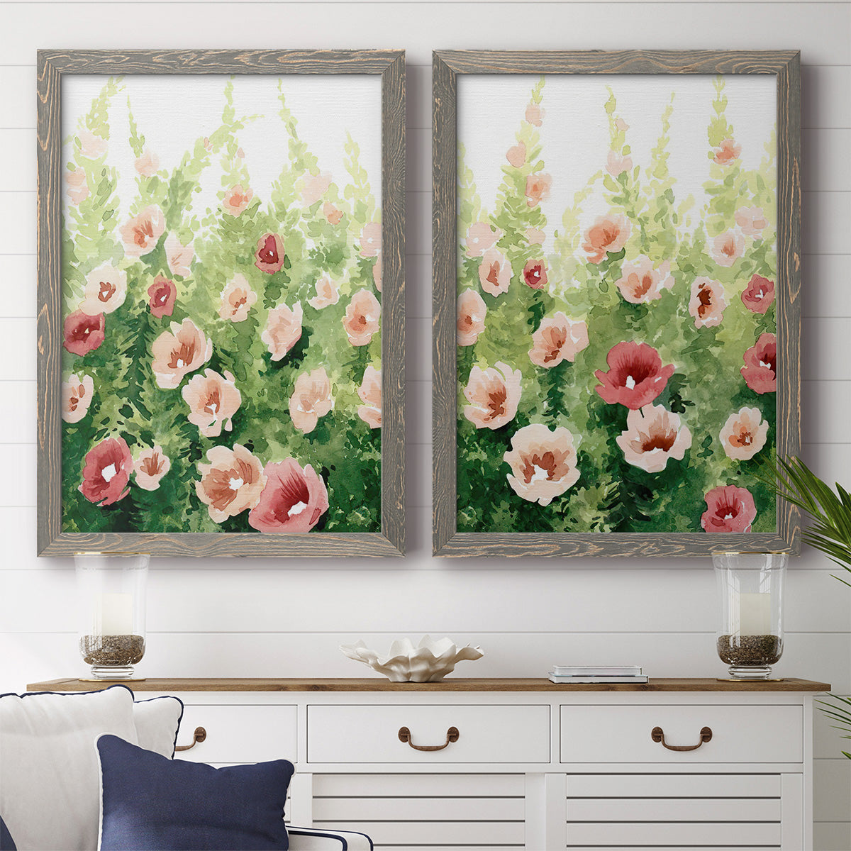 Set of two gray barnwood framed canvas prints depicting a coordinated art pair of a field of pink coral and white flowers rendered as luminous impressionistic floral paintings above a dining room sideboard.