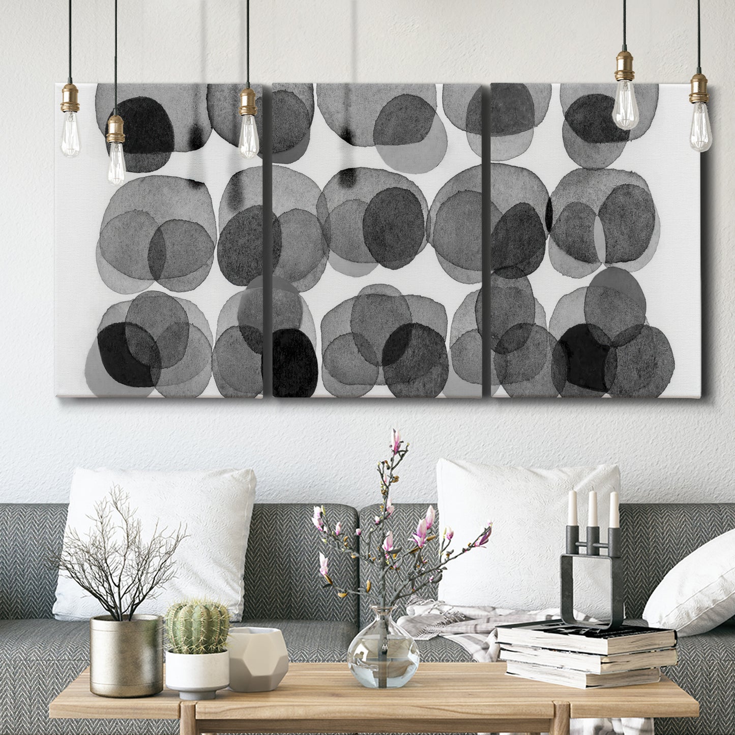 Three-panel canvas wall art featuring geometric abstract watercolor forms, displayed in a modern living room above seating.