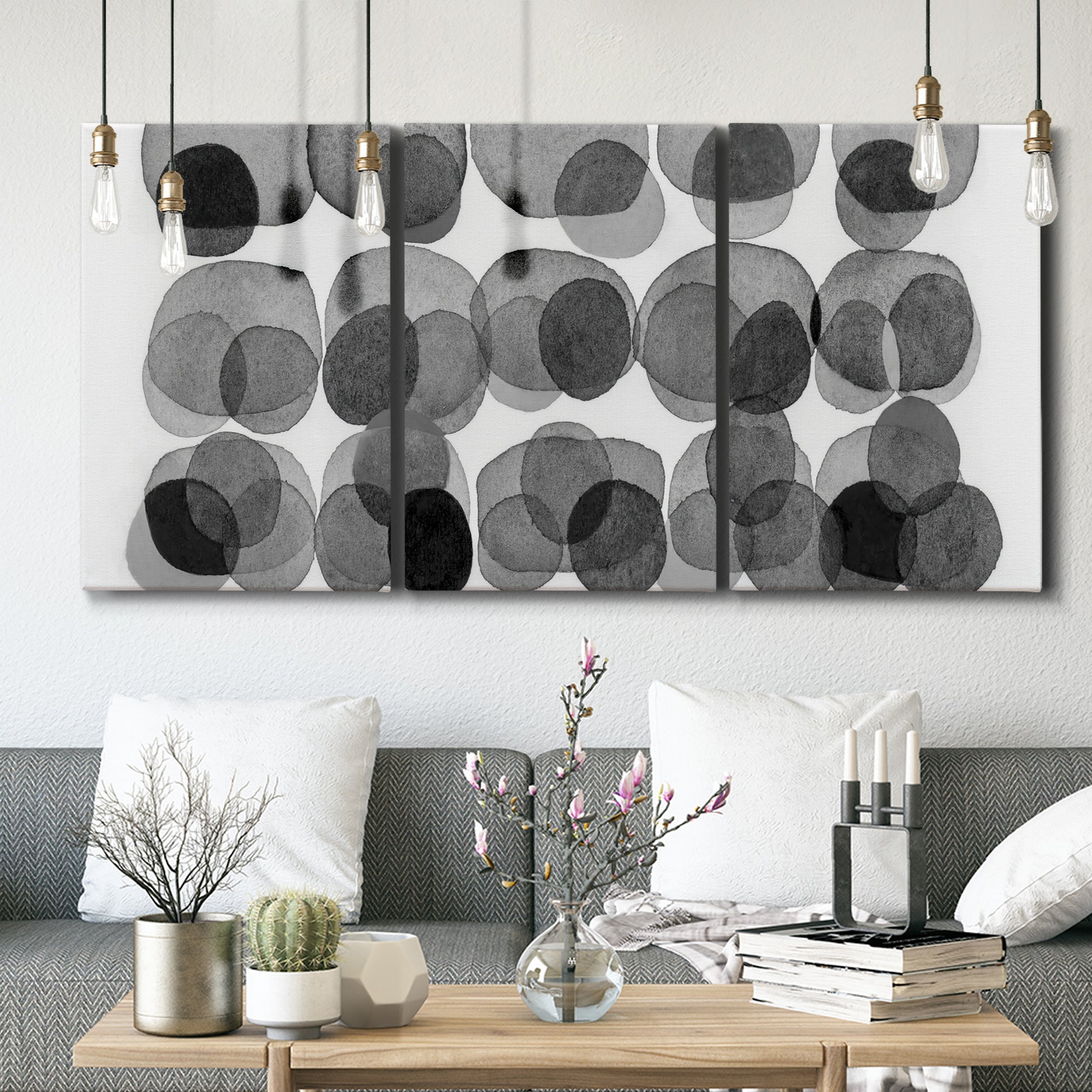 Three-panel canvas wall art featuring geometric abstract watercolor forms, displayed in a modern living room above seating.