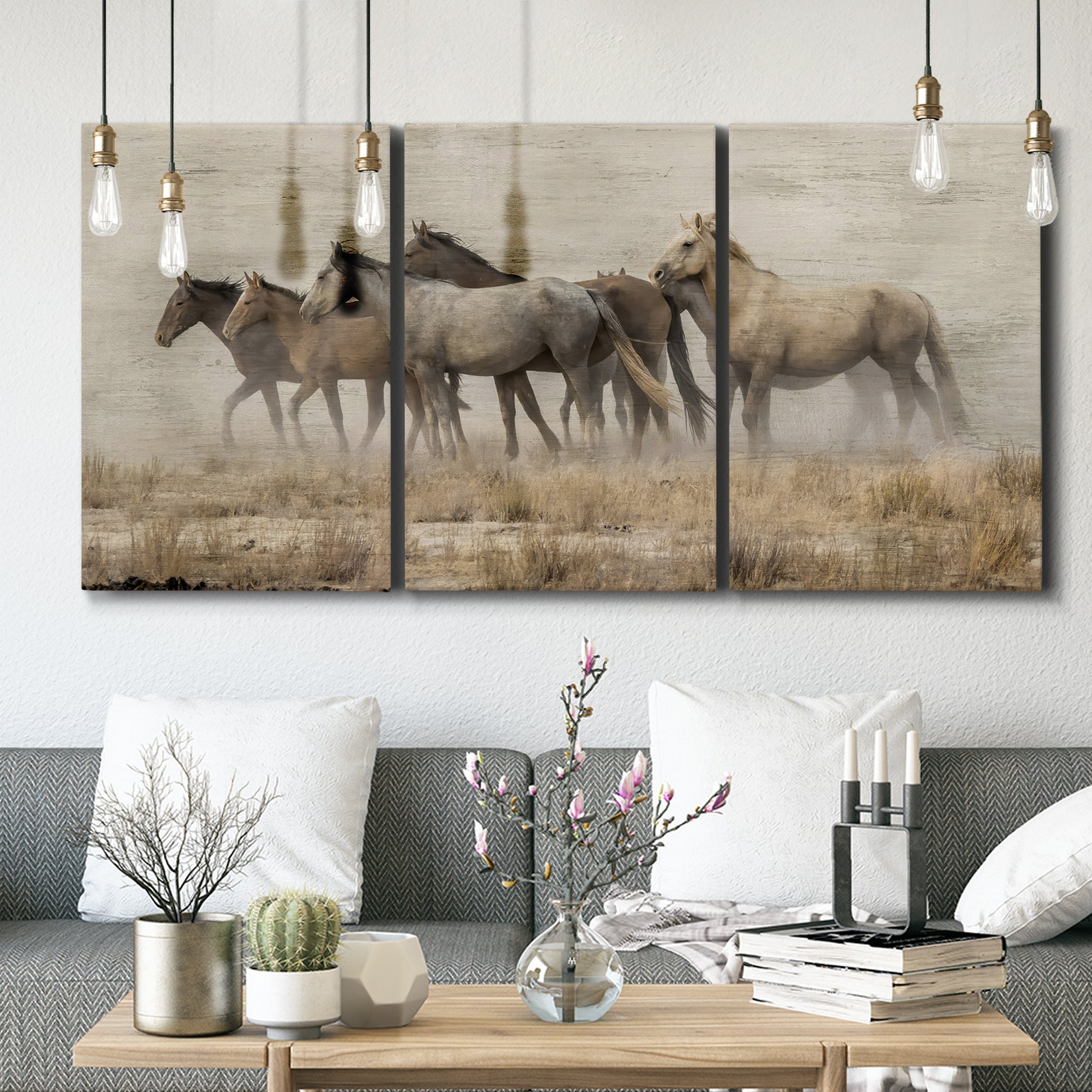 Three-panel canvas wall art featuring wild horses roaming open terrain, displayed in a modern living room above seating.
