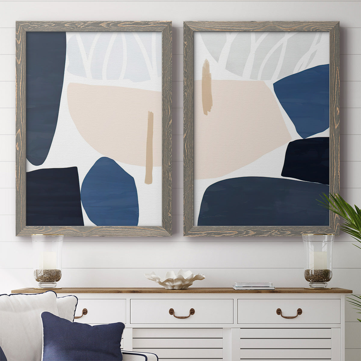 Set of two gray barnwood framed canvas prints depicting a coordinated art pair of large navy cream and beige organic geometric shapes rendered as minimalist color-block abstracts above a dining room sideboard.