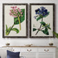Set of two black barnwood framed canvas prints depicting a coordinated art pair of colorful flowering plant specimens rendered as antique botanical plate illustrations above a dining room sideboard.