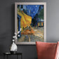 Impressionist night café street scene by Vincent van Gogh in an ornate weathered white frame displayed in a dark-toned interior setting.