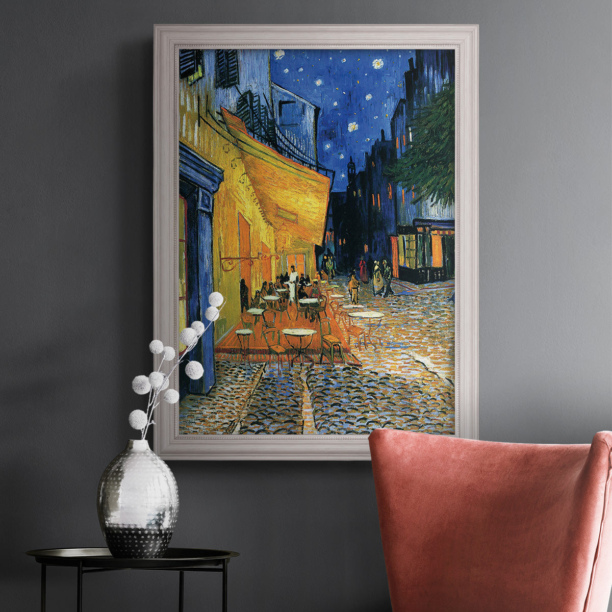 Impressionist night café street scene by Vincent van Gogh in an ornate weathered white frame displayed in a dark-toned interior setting.